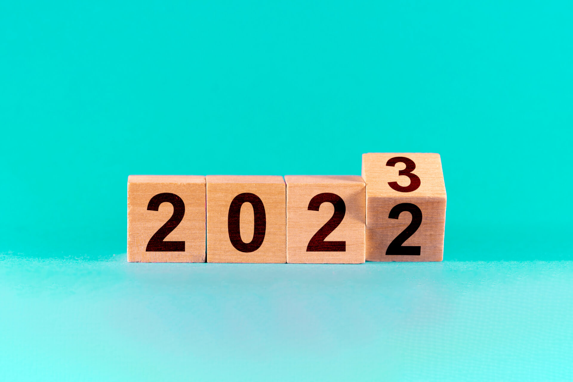 Concept of the end of 2022 and the new beginning in 2023. Change from 2022 to 2023 in wooden cubes on a green background.