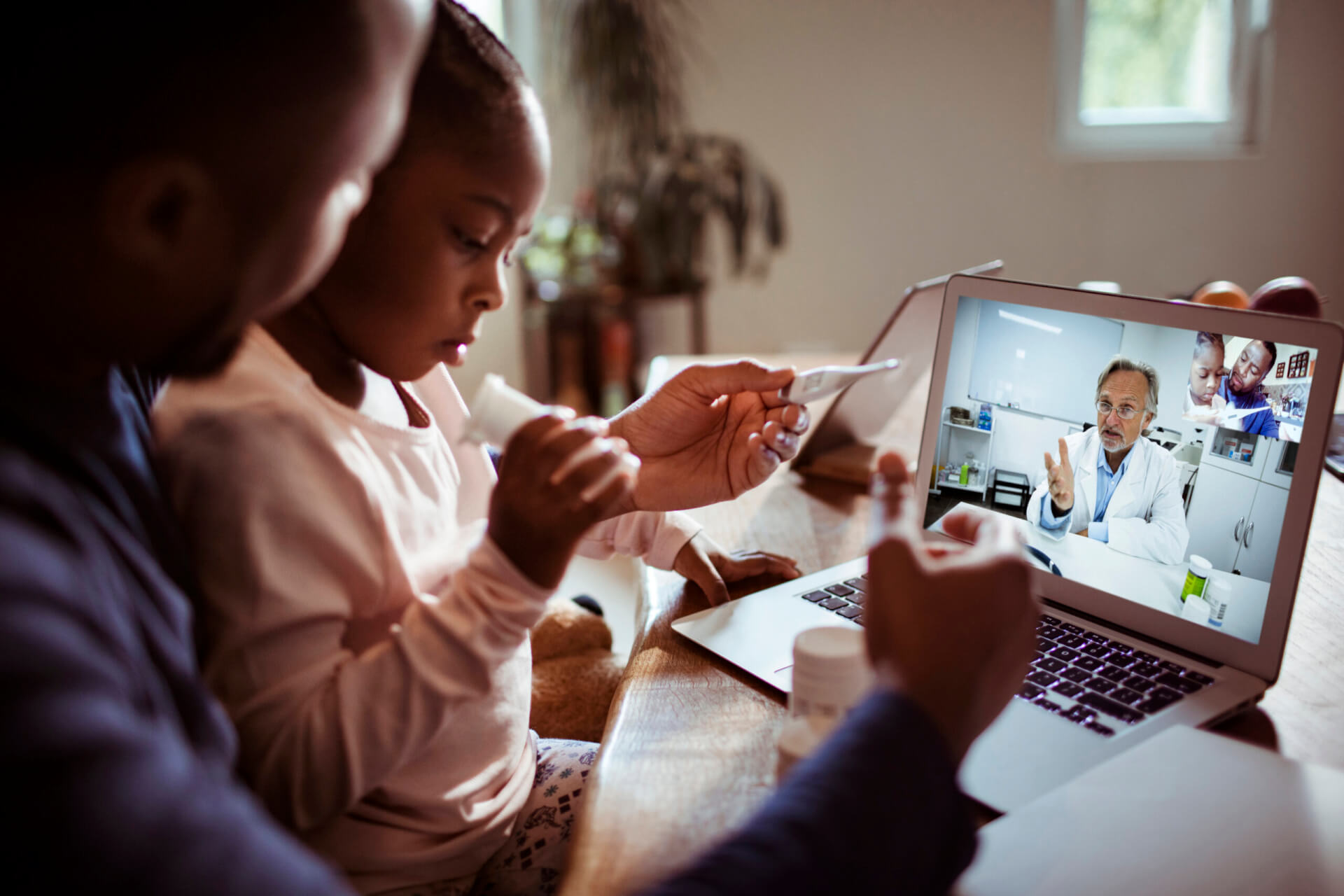 Close up of a father and daughter having a video call with their doctor